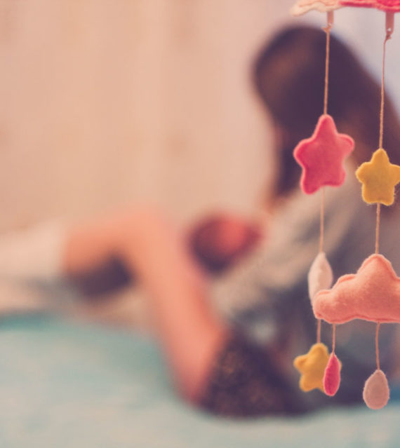 Woman breastfeeding, blurred background with baby mobile in foreground